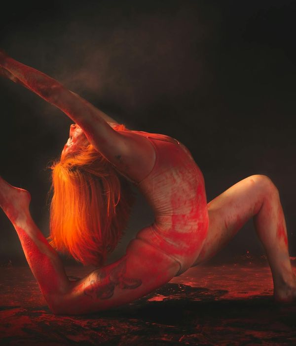 Woman performing a graceful yoga stretch in a dark amber room